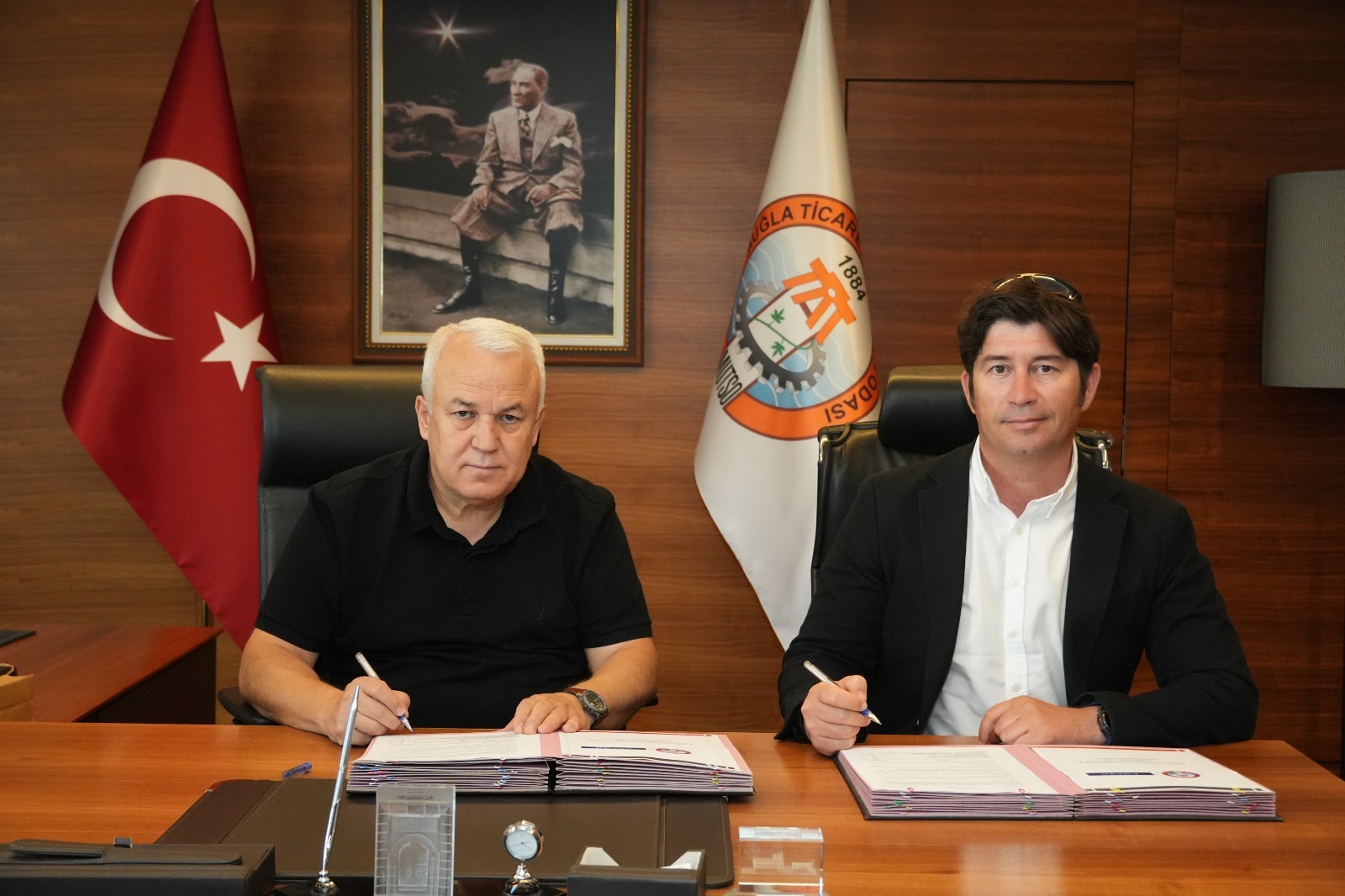 MUTSO Yönetim Kurulu Başkanı ve Kalynda Teknoloji kurucusu Serkan Arslan, MUTSO başkanlık makamında iş birliği protokolünü imzalarken